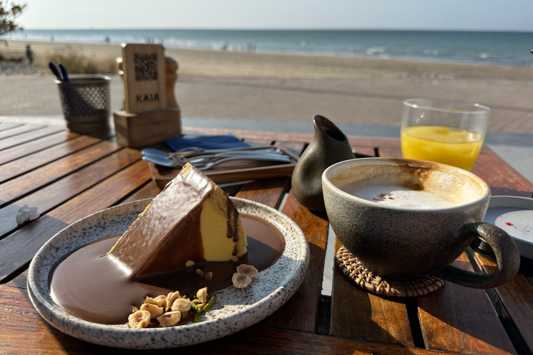 Cheese cake, coffee and juice on table overlooking Qurum Beach