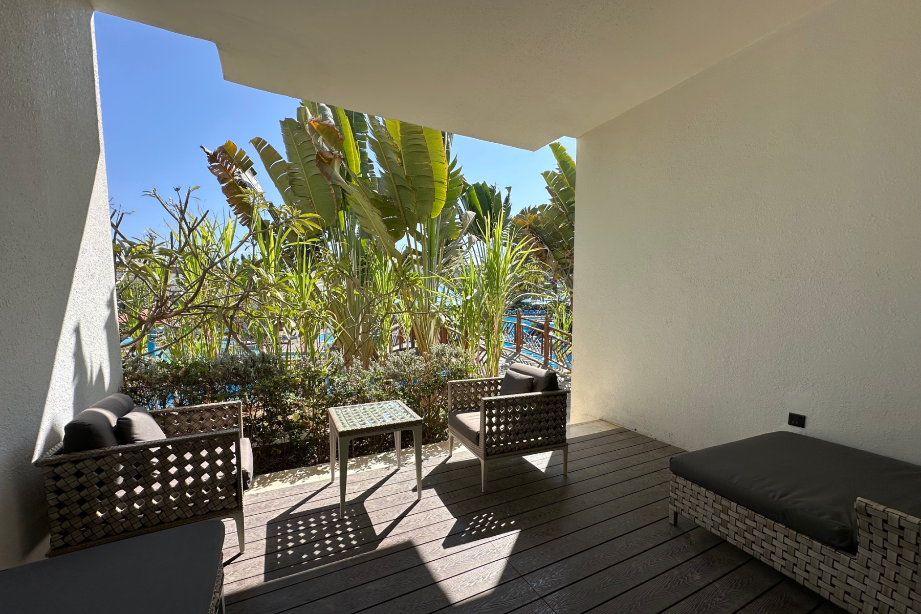 Seating on the covered deck of our villa facing palm trees planted in front of the lazy river