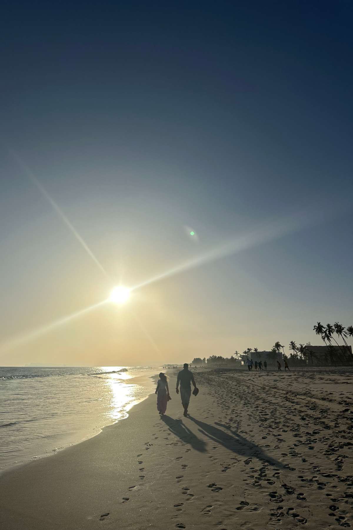 My husband and daughter walking along the sand on Al Baleed Beach at sunset