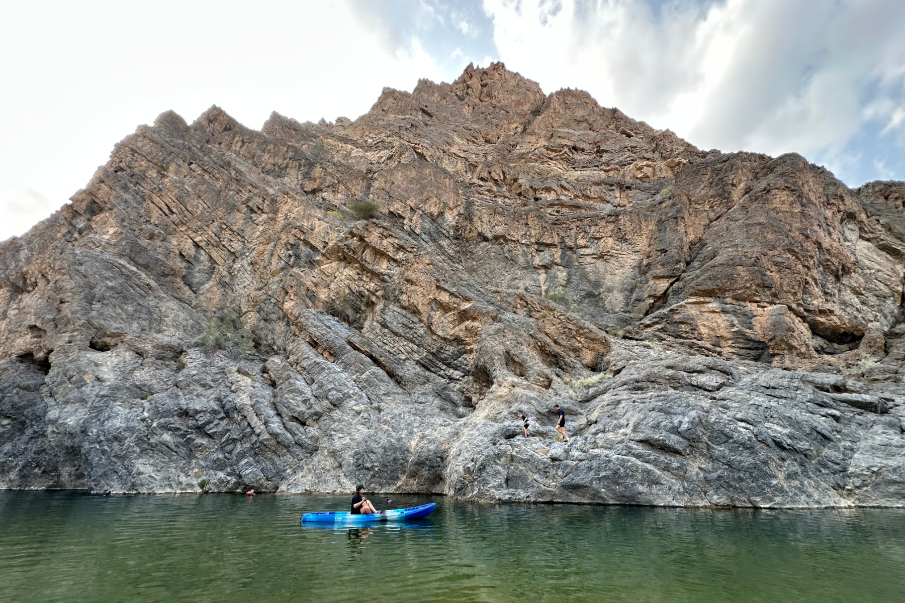 Paddling in a canoe in the pool beside the hotel in Wadi Al Arbeieen. The layered cliff rises to the sky