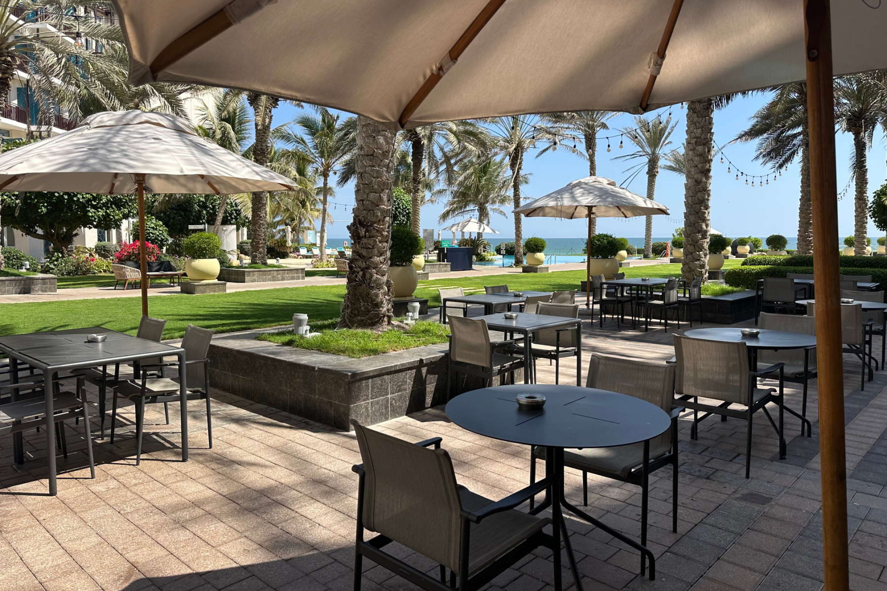Outdoor dining area at the Crowne Plaza. There are tables with umbrellas shading them from the sun