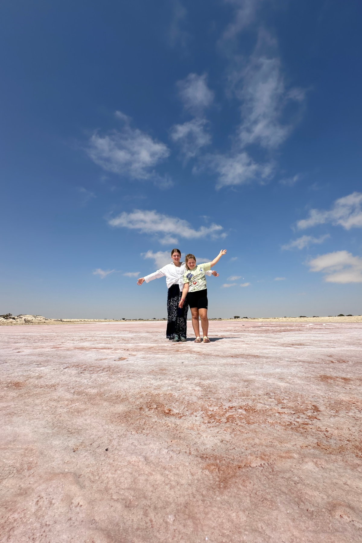 My children striking a pose on the dry salty bed of a pink lagoon at Khahil