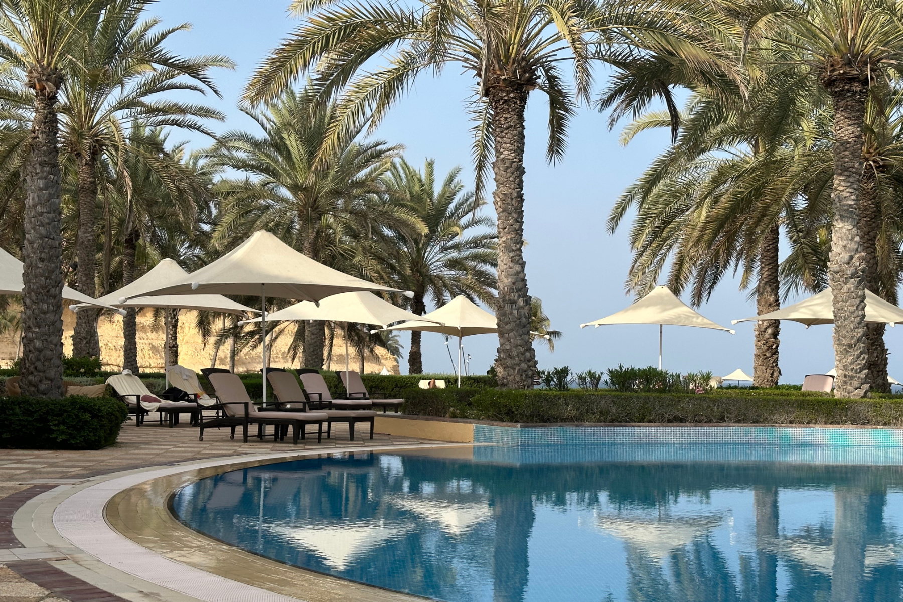 Umbrellas and sun loungers beside the swimming pool at the Hilton Al Bandar hotel