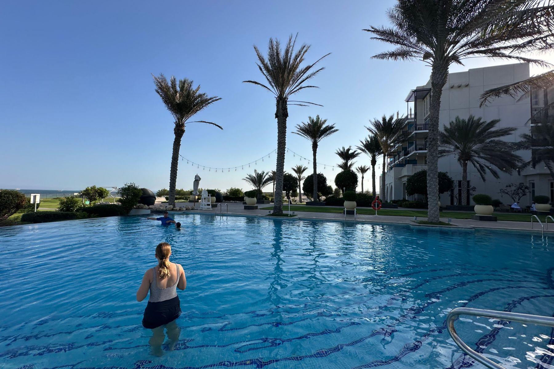 My daughter in the outdoor pool with palm trees in the background