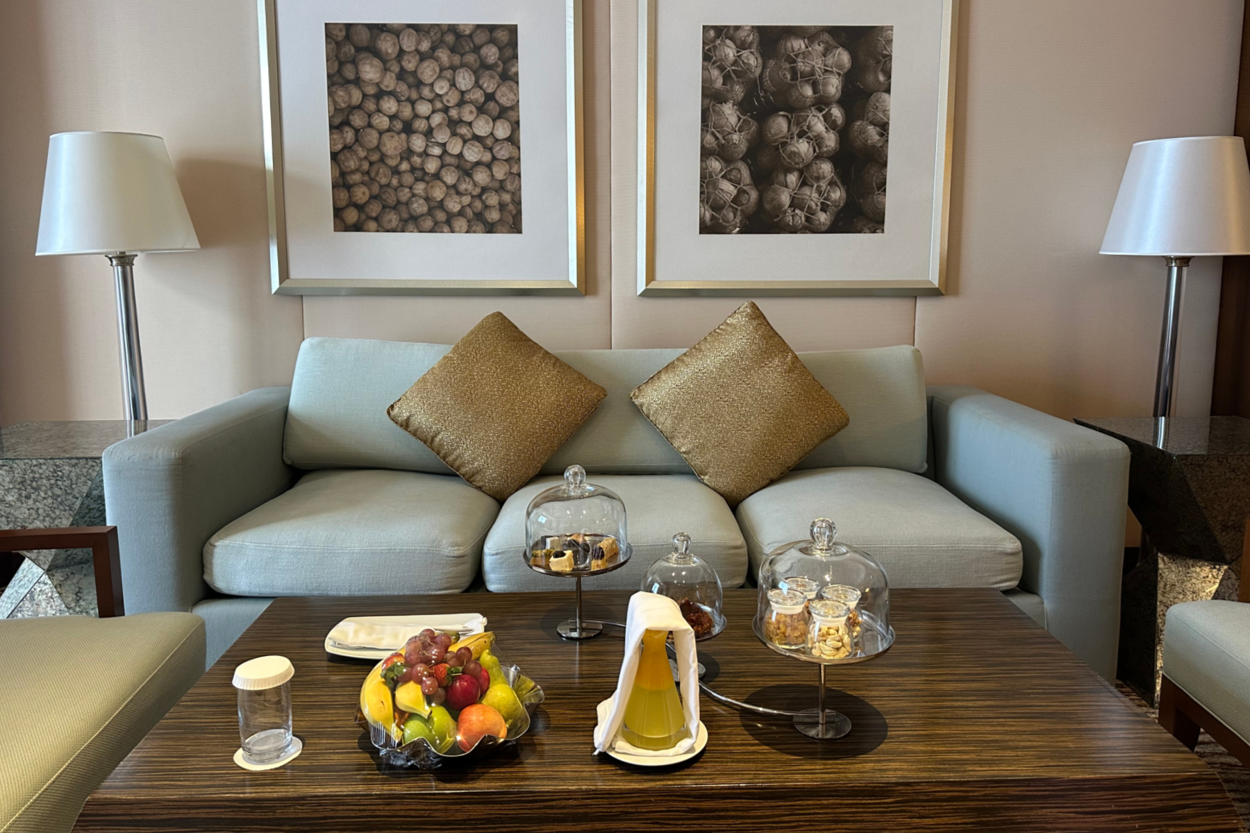 Sitting room at in the executive suite at the Crowne Plaza with three seater settee and coffee table. There are fruits, juice and cakes on the table