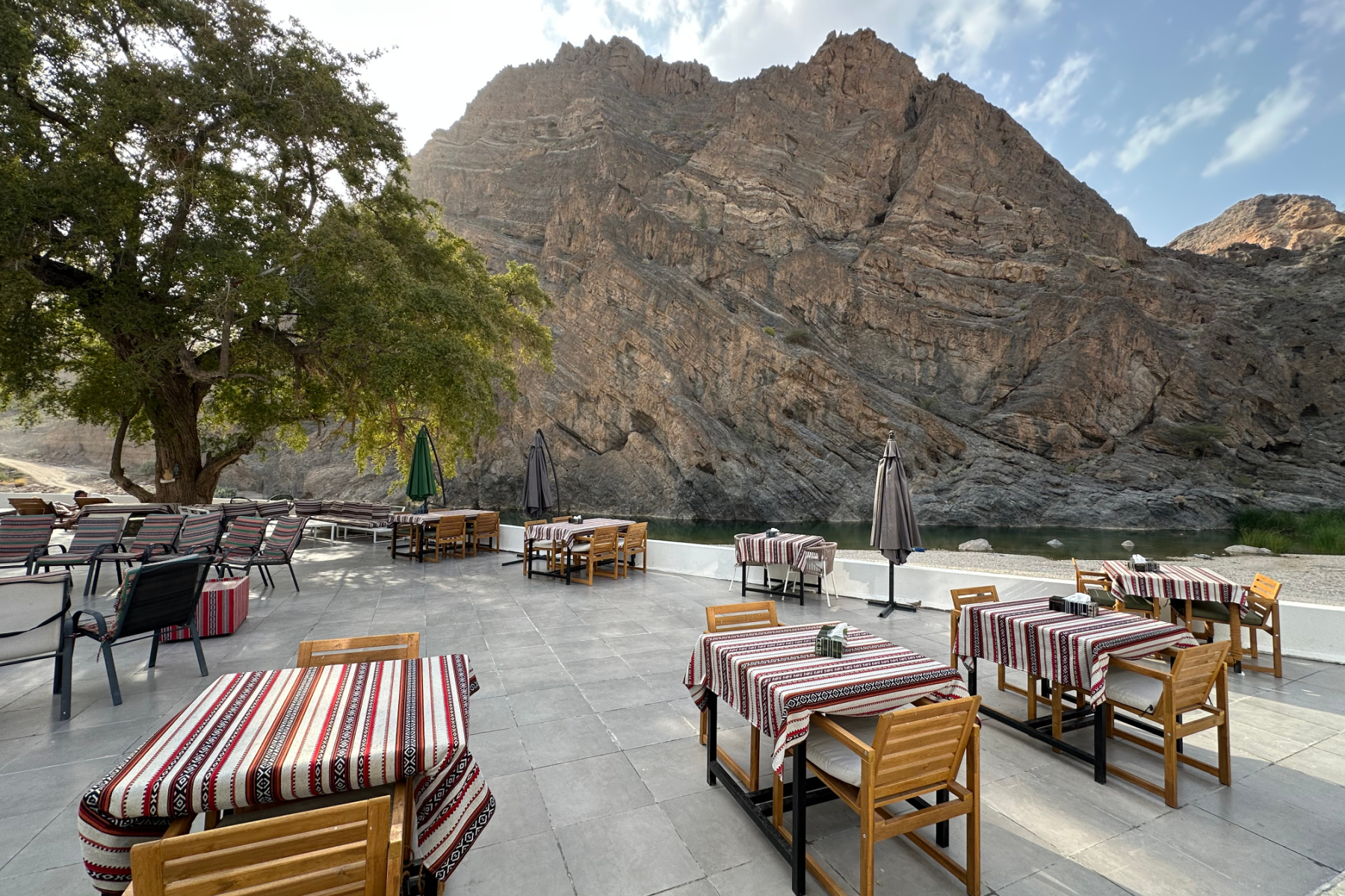The outdoor seating and dining space at the hotel with the wadi cliffs in the background