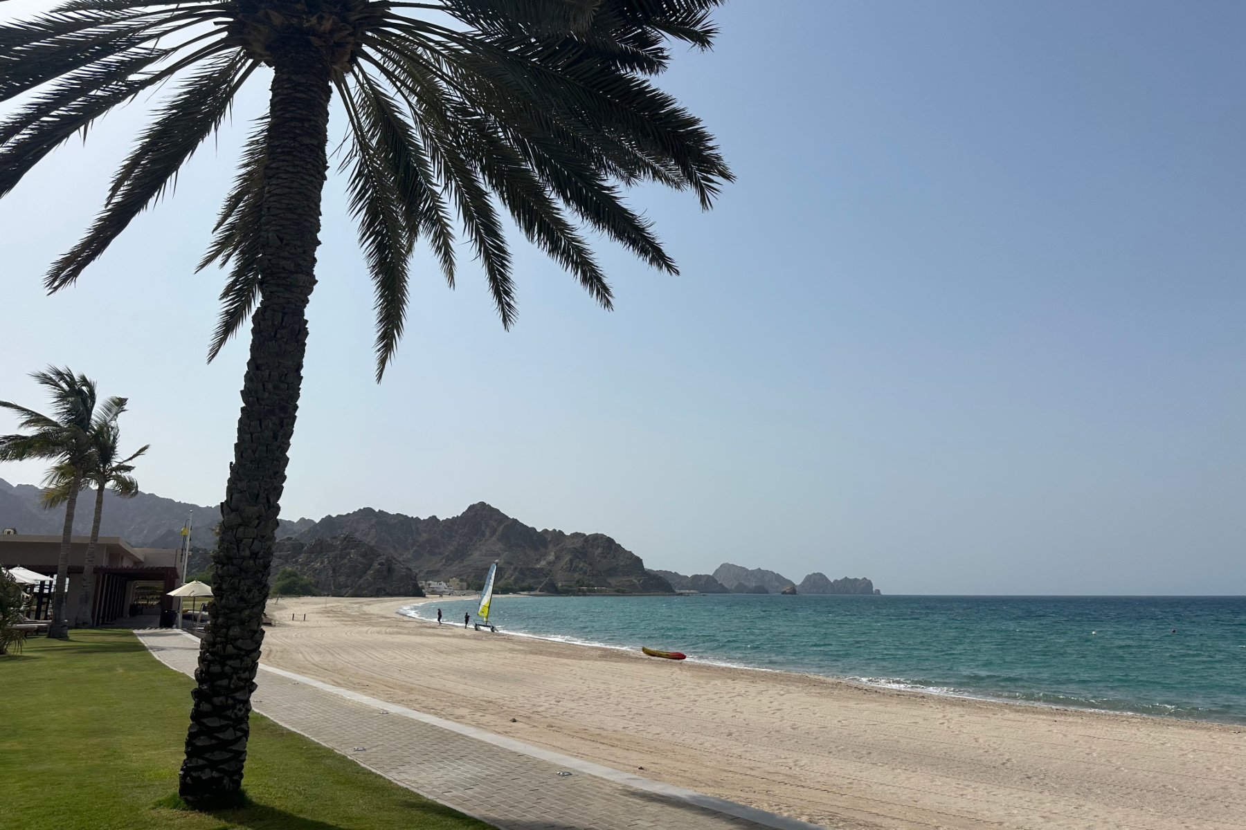 The 1km long beach in front of Al Bustan Palace with palm trees and turquoise water lapping the white sandy shore