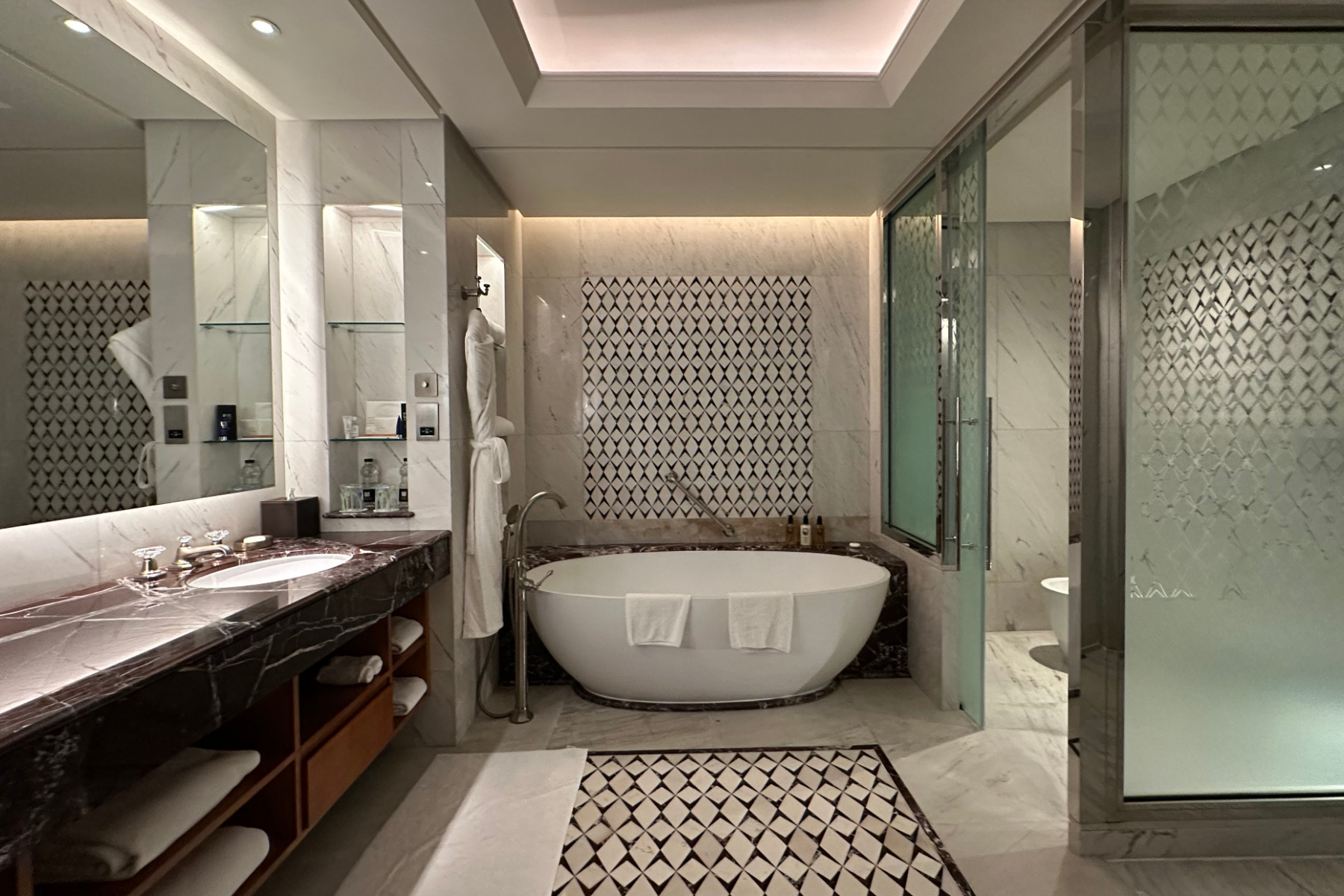 Bathroom in the master bedroom of the Sohar Presidential Suite at Al Bustan Palace. There is a walk in toilet and shower to the right, sinks to the left and a free standing white bath at the far end of the room