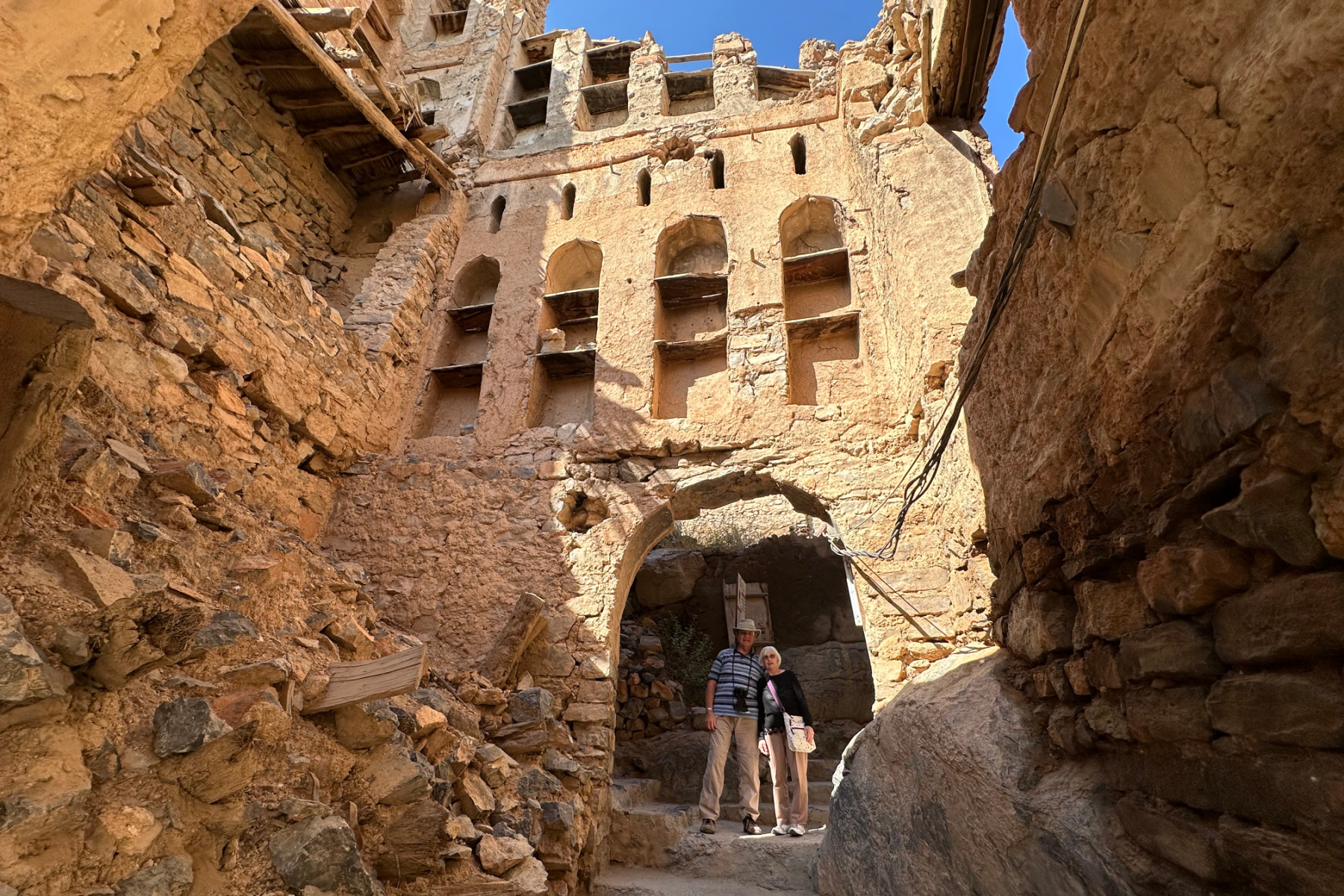 My parents stood in a doorway underneath a mud stone building in the mountain village of Misfat Al Abriyeen