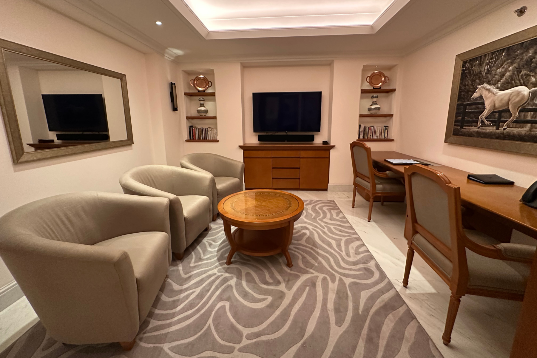 The office in the Sohar Presidential Suite. There are three bucket chairs, a desk and TV