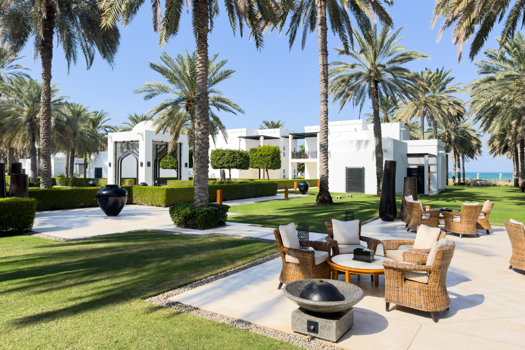 The lush green gardens and outdoor seating between villas at The Chedi luxury hotel in Muscat