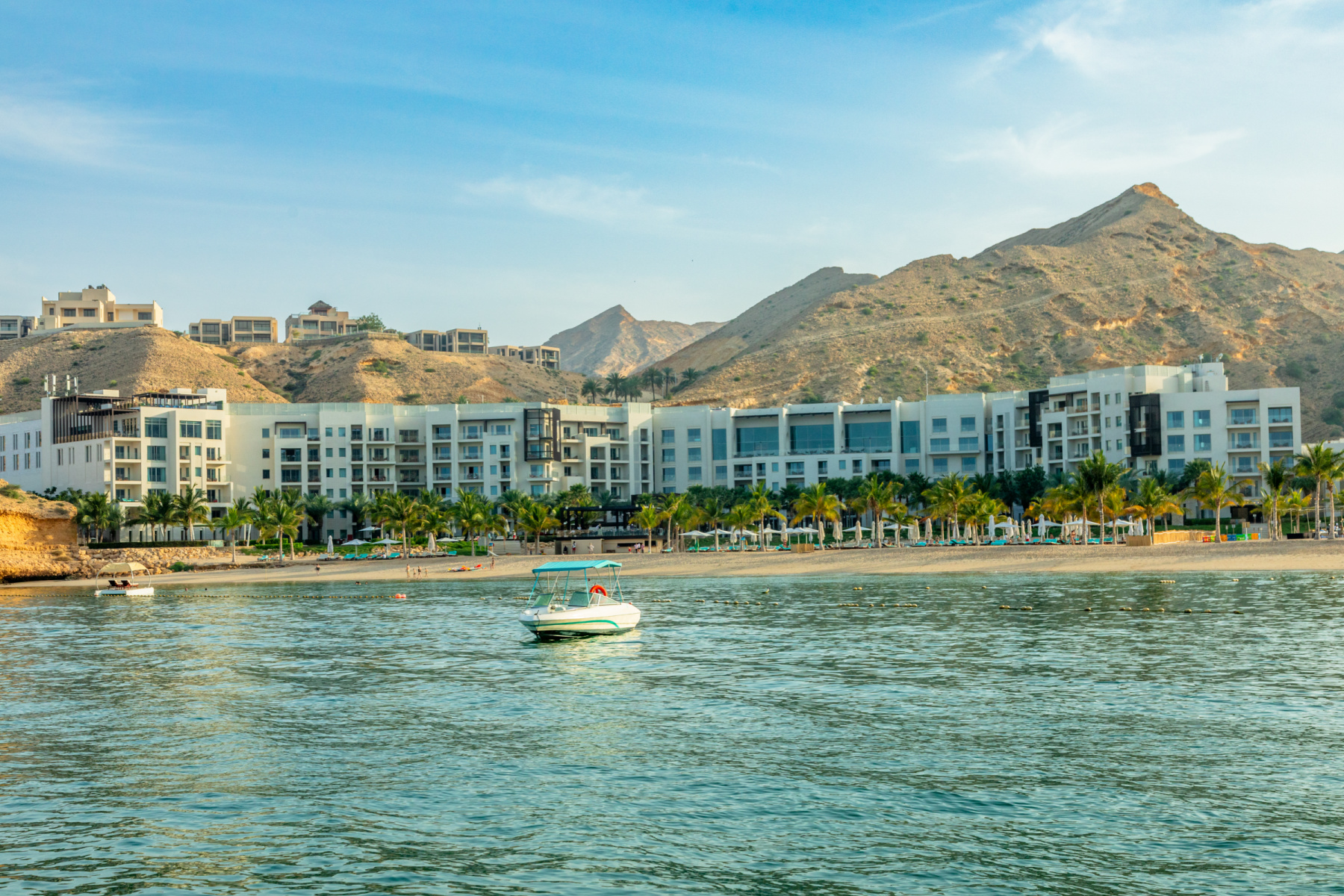 A view of Jumeirah Muscat Bay on the shore view from the sea bay with mountains in the background, Muscat, sultanate Oman