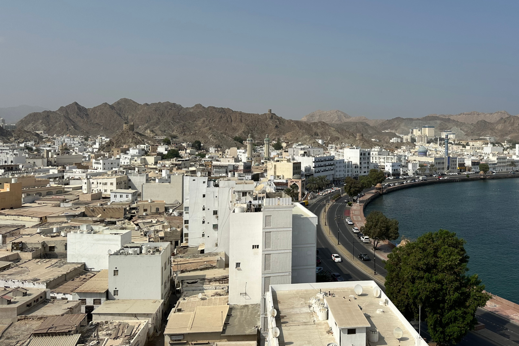 The view from Muttrah Fort inland over the homes and businesses towards the mountains where you can see a small watchtower on the horizon