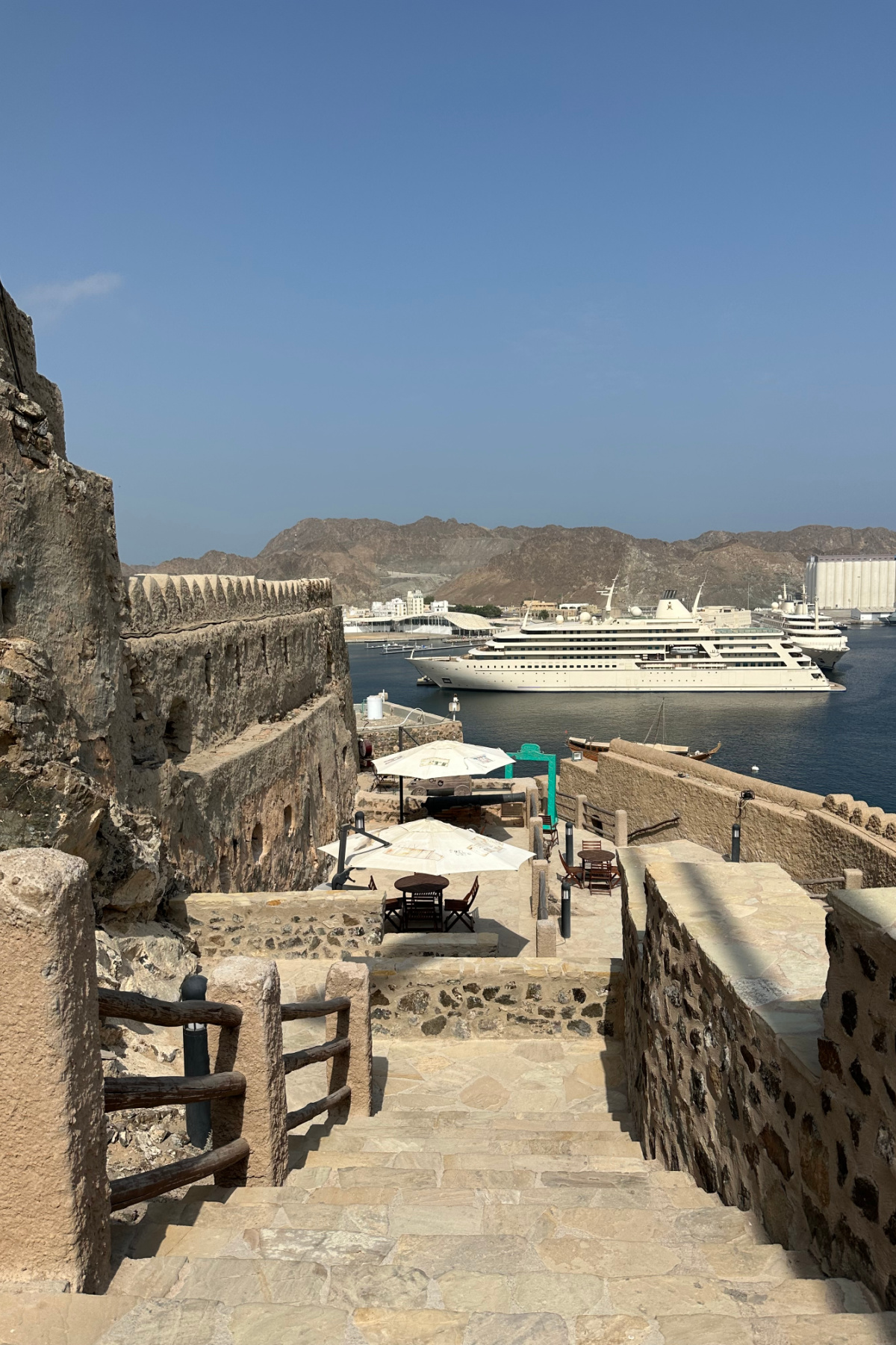 Looking down the battlements of Muttrah Fort towards the port where a royal yacht is moored