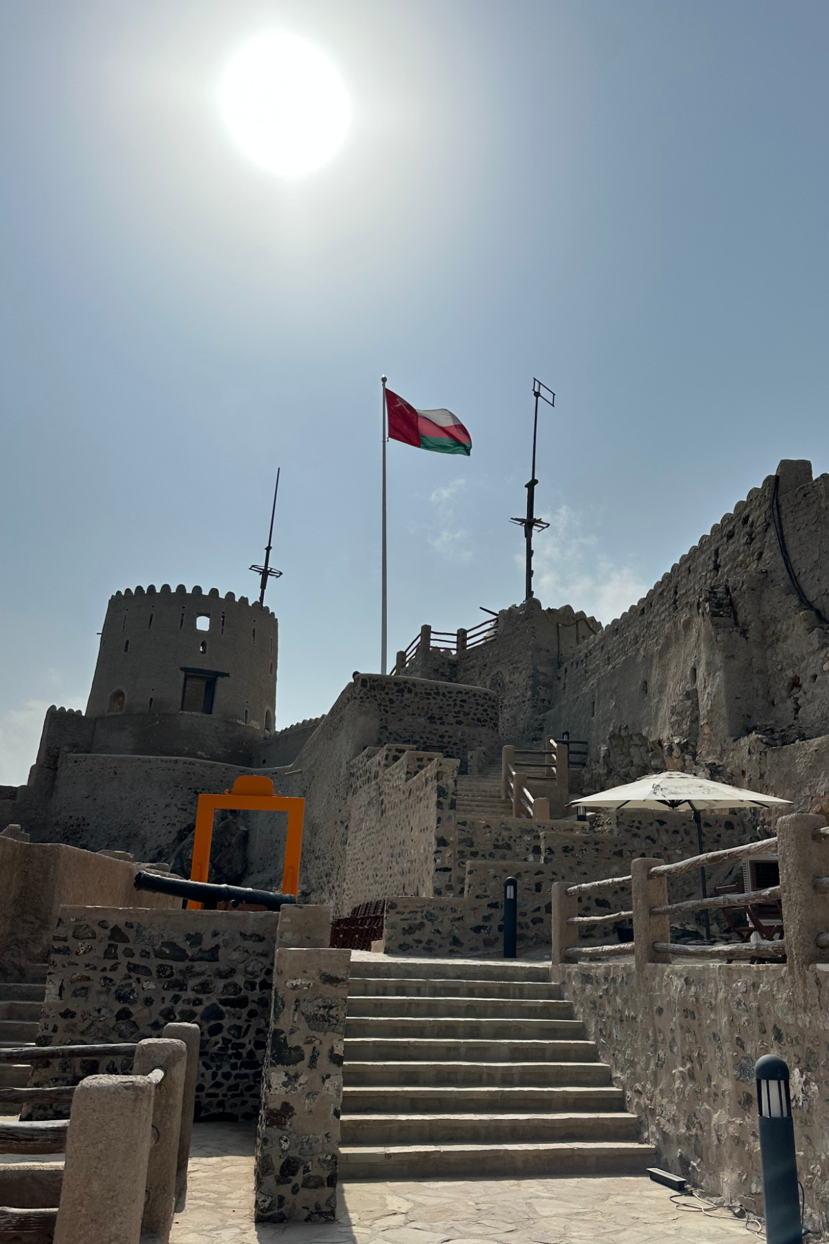 Looking up the battlements of Muttrah Fort towards the top tower and an Omani flag