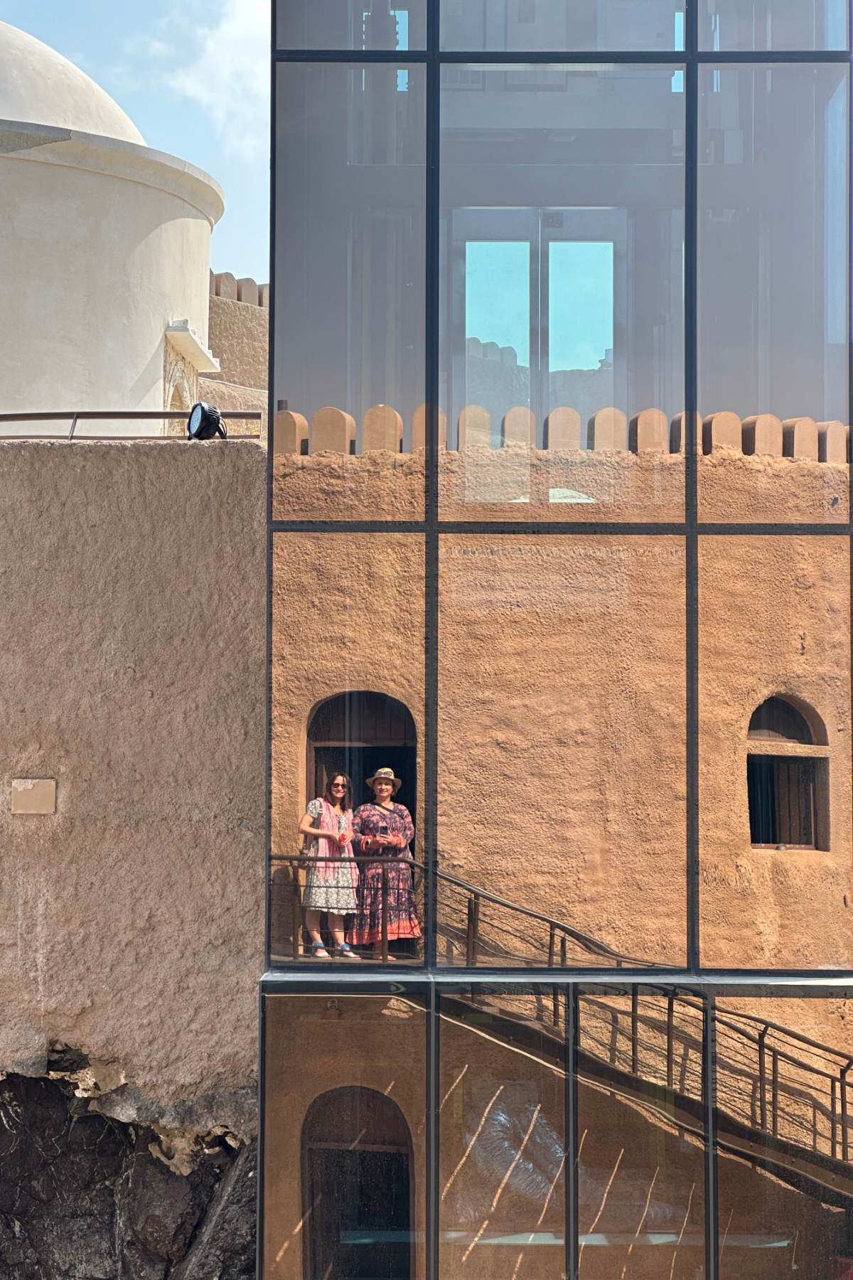 A reflection of my friend and I in the glass lift shaft at Al Mirani Fort